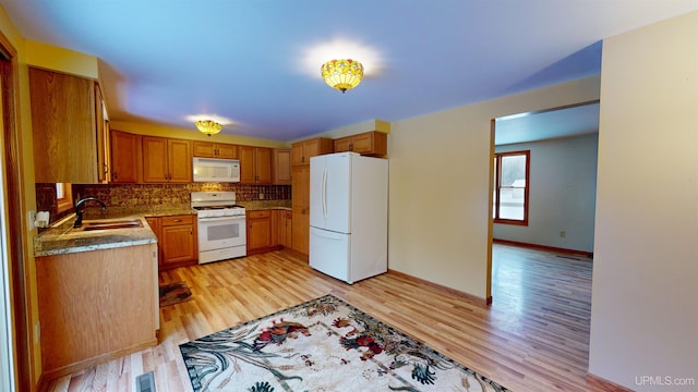 kitchen with white appliances, sink, decorative backsplash, light hardwood / wood-style floors, and light stone counters