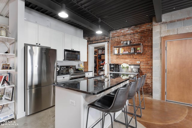 kitchen with a kitchen bar, stainless steel appliances, sink, white cabinets, and an island with sink