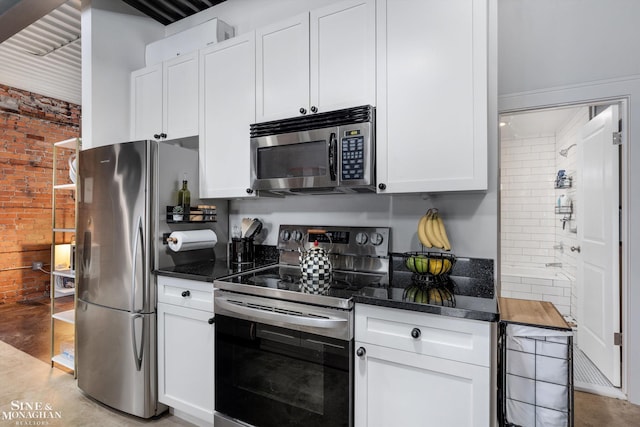 kitchen featuring brick wall, white cabinetry, and appliances with stainless steel finishes