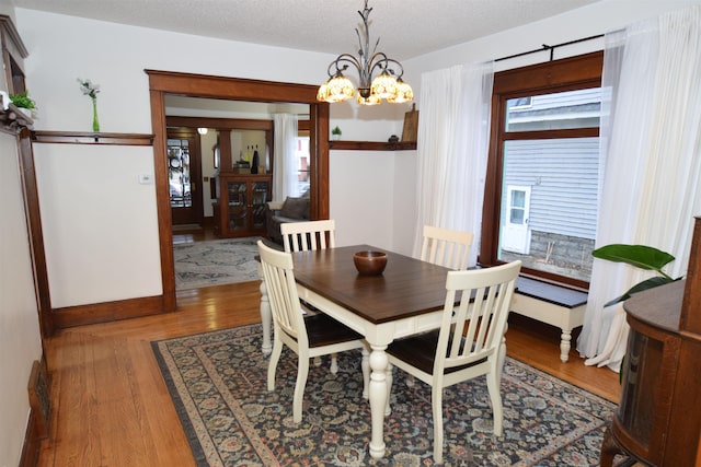 dining space with a chandelier, hardwood / wood-style floors, and a textured ceiling