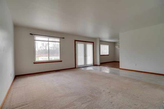 carpeted spare room featuring a notable chandelier