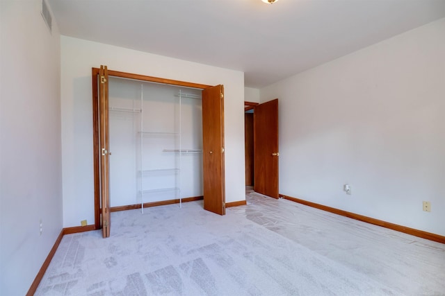 unfurnished bedroom featuring light carpet and a closet