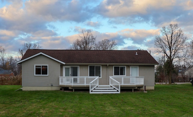 back house at dusk featuring a yard and a deck