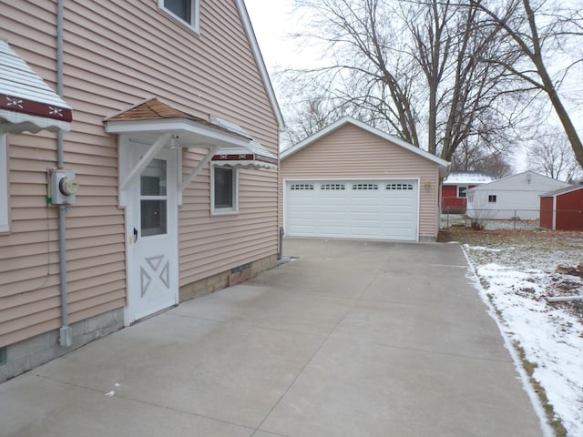 snow covered property with a garage and an outbuilding