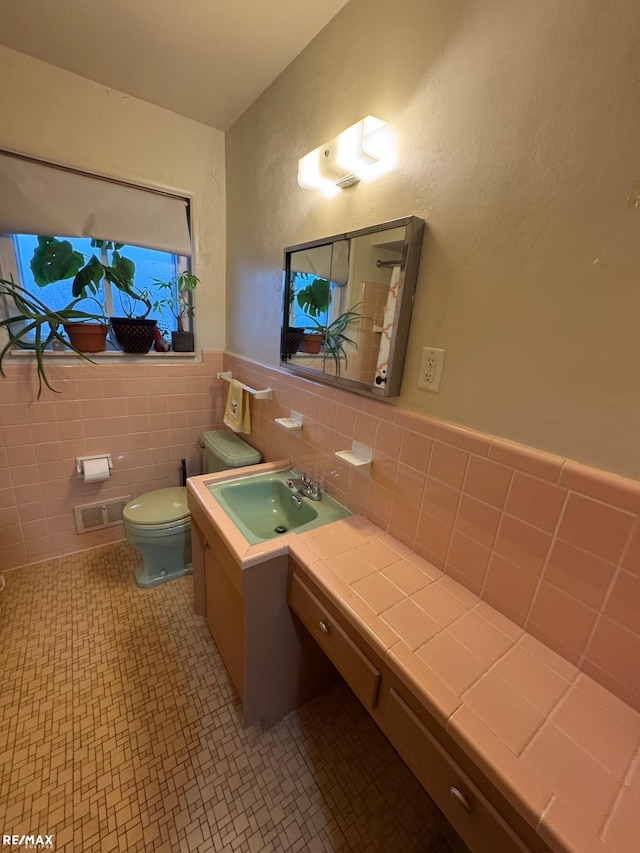 bathroom featuring tile patterned floors, vanity, tile walls, and toilet