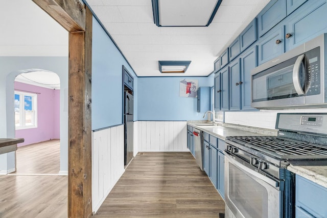 kitchen with stainless steel appliances, blue cabinets, ornamental molding, and sink