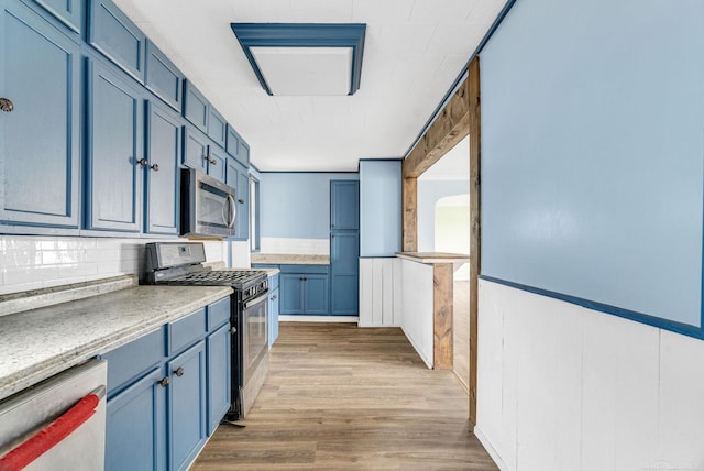 kitchen featuring light wood-type flooring, stainless steel appliances, and blue cabinets