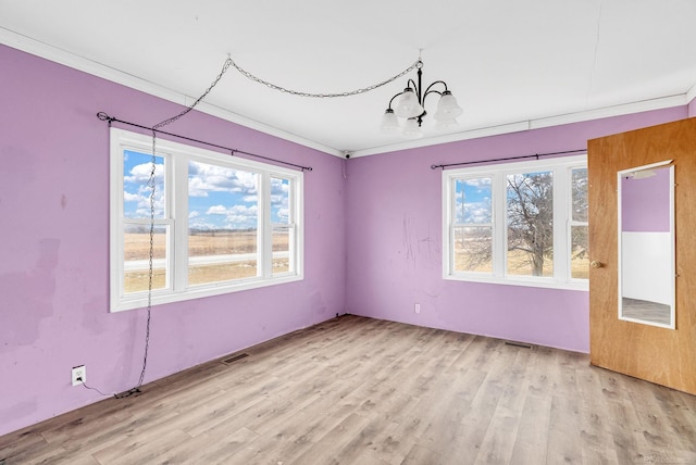 unfurnished room with crown molding, a chandelier, and light wood-type flooring