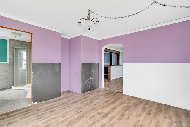 unfurnished room with wood-type flooring, ornamental molding, and an inviting chandelier