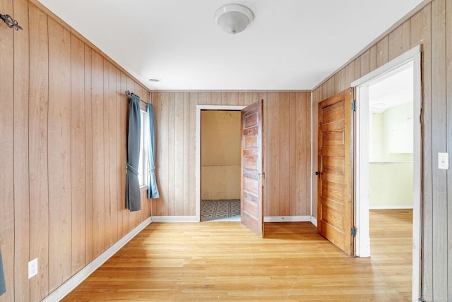 spare room featuring light hardwood / wood-style floors and wood walls