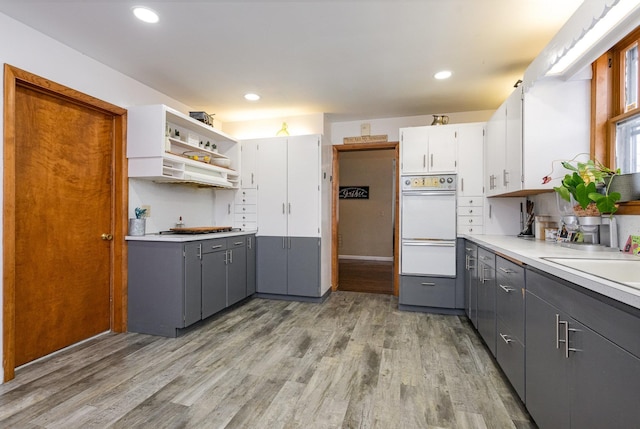 kitchen with premium range hood, gray cabinetry, oven, light hardwood / wood-style flooring, and white cabinetry