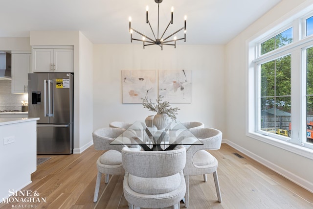 dining room with light hardwood / wood-style flooring and a notable chandelier