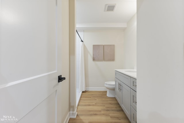 bathroom featuring hardwood / wood-style flooring, vanity, toilet, and walk in shower