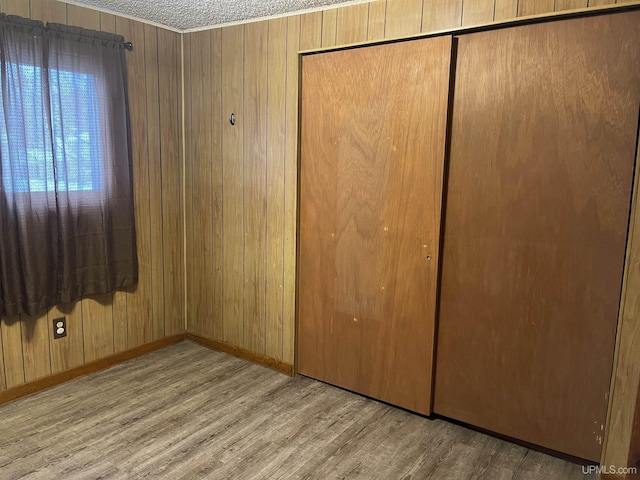 unfurnished bedroom featuring wood walls, light hardwood / wood-style floors, and a closet