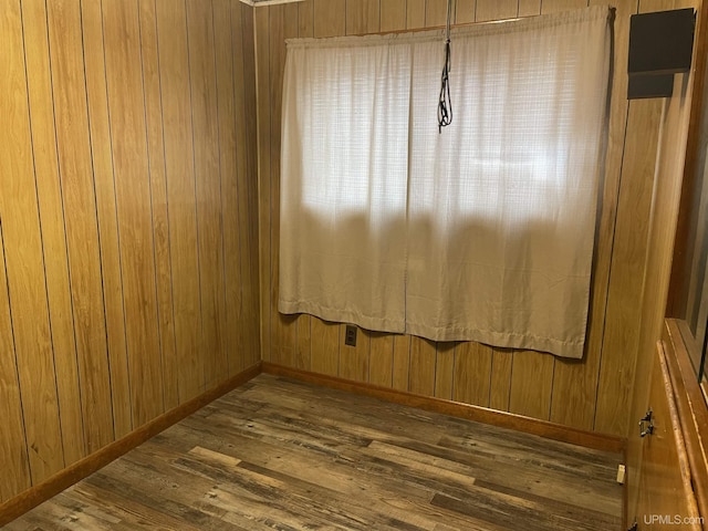 unfurnished room featuring dark hardwood / wood-style floors and wood walls