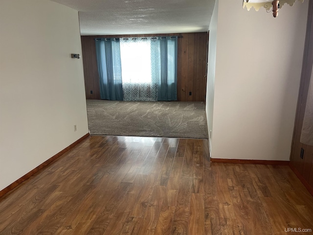 spare room featuring a textured ceiling and dark hardwood / wood-style flooring