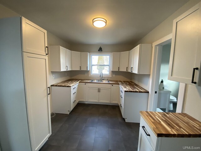 kitchen featuring white cabinetry, butcher block counters, and sink