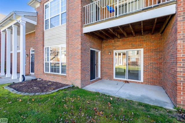 view of exterior entry featuring a balcony and a patio