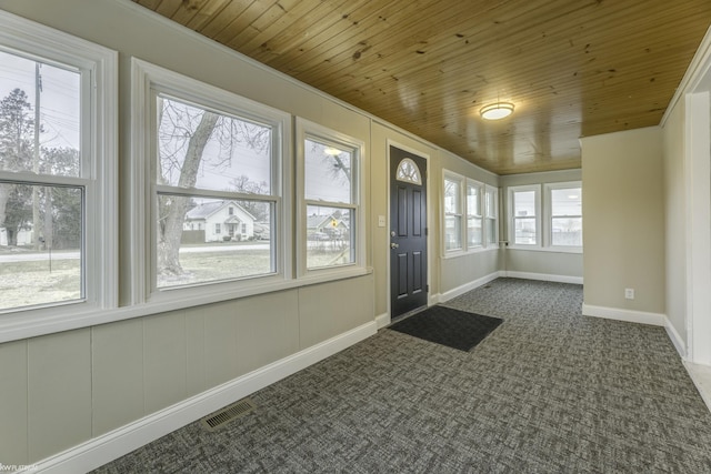 doorway with dark colored carpet, wooden ceiling, and ornamental molding