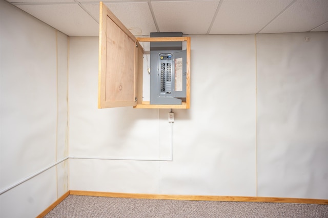 basement featuring carpet, a drop ceiling, and electric panel