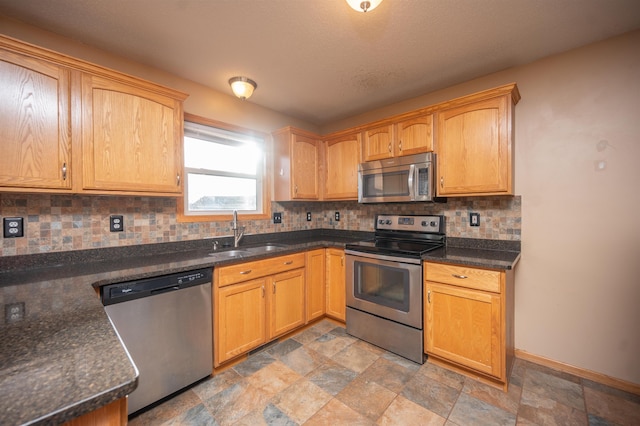 kitchen with decorative backsplash, appliances with stainless steel finishes, dark stone counters, and sink