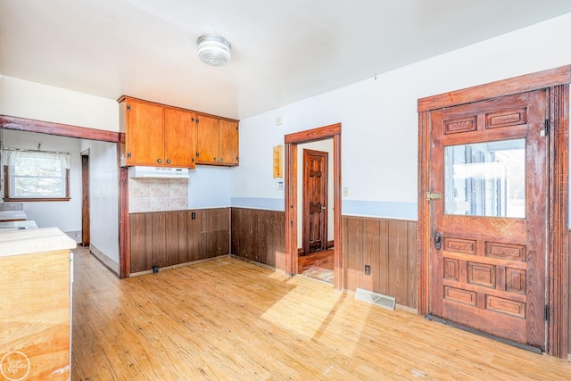 kitchen with wooden walls and light hardwood / wood-style flooring