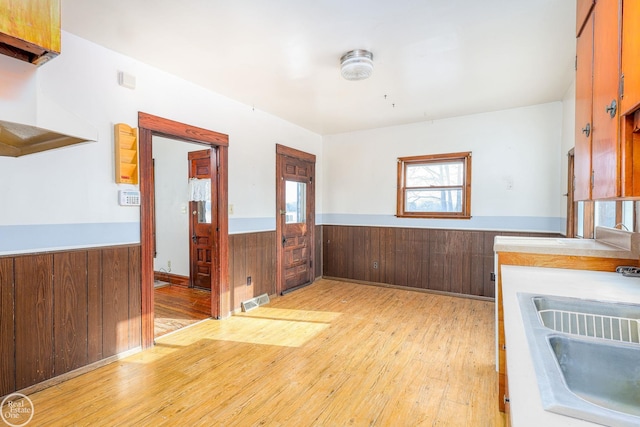 interior space featuring sink, light hardwood / wood-style flooring, and wood walls