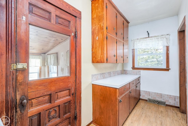 kitchen with plenty of natural light, light hardwood / wood-style floors, and wooden ceiling