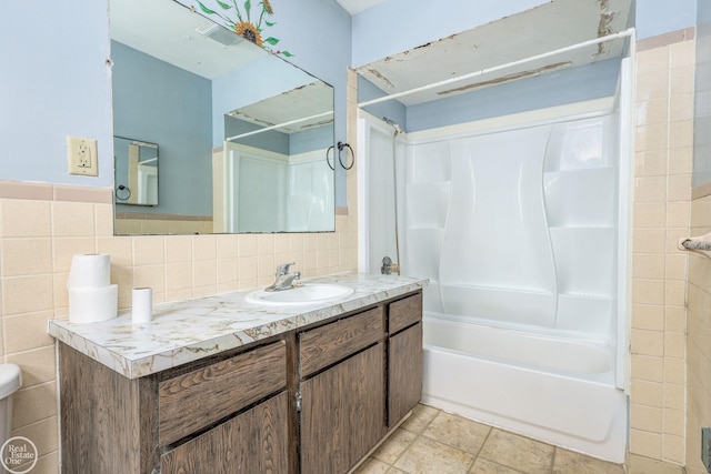 bathroom with shower / bathing tub combination, vanity, and tile walls