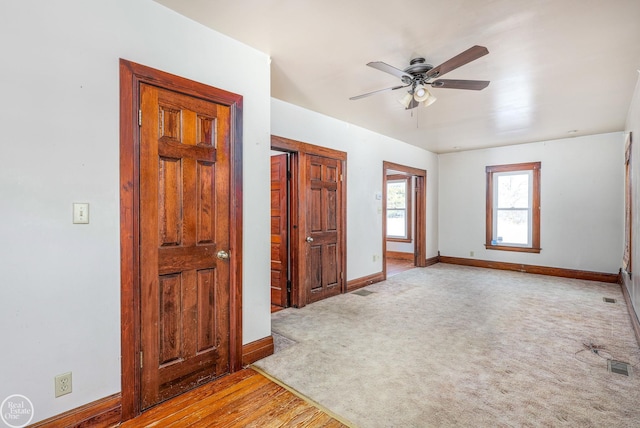 empty room featuring ceiling fan and light colored carpet