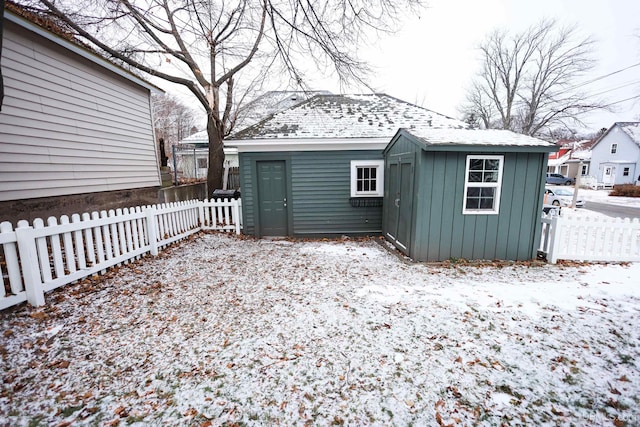 snow covered back of property featuring an outbuilding