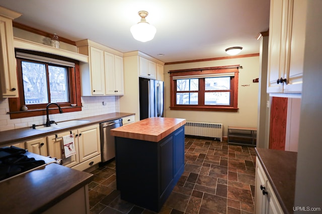 kitchen featuring sink, a center island, radiator heating unit, butcher block countertops, and appliances with stainless steel finishes