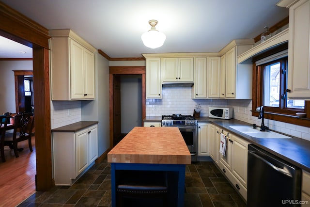 kitchen with sink, wooden counters, stainless steel appliances, and cream cabinetry