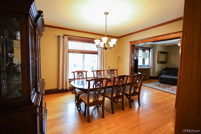 dining area featuring light wood-type flooring, ornamental molding, and an inviting chandelier