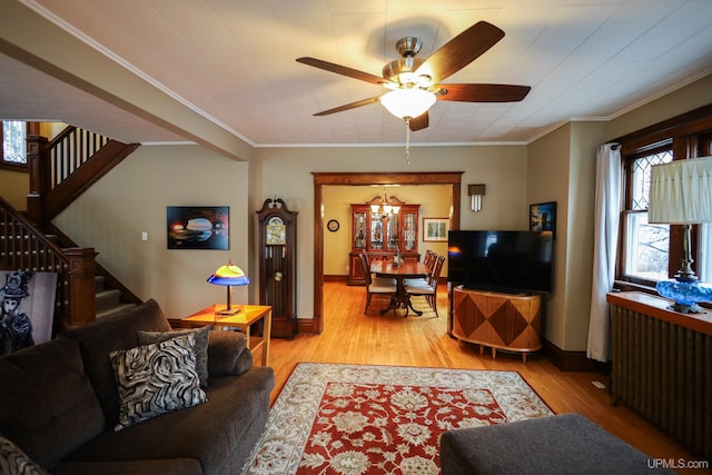 living room featuring ceiling fan with notable chandelier, crown molding, and light hardwood / wood-style flooring