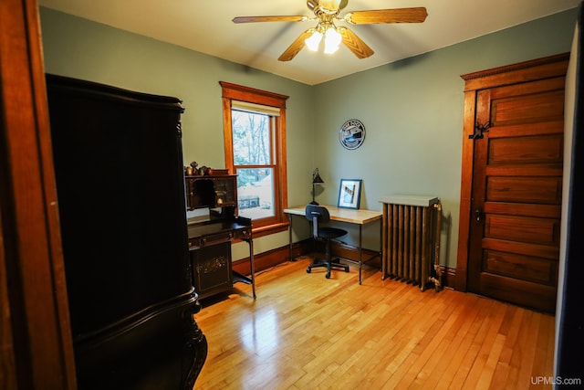 home office with light hardwood / wood-style floors, radiator, and ceiling fan