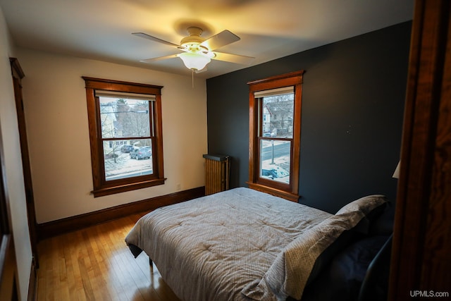 bedroom with ceiling fan, radiator heating unit, and light hardwood / wood-style floors