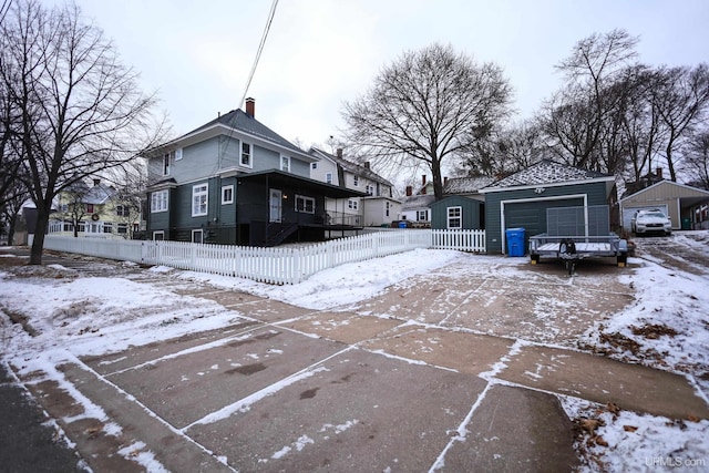 snow covered house featuring a garage and an outdoor structure