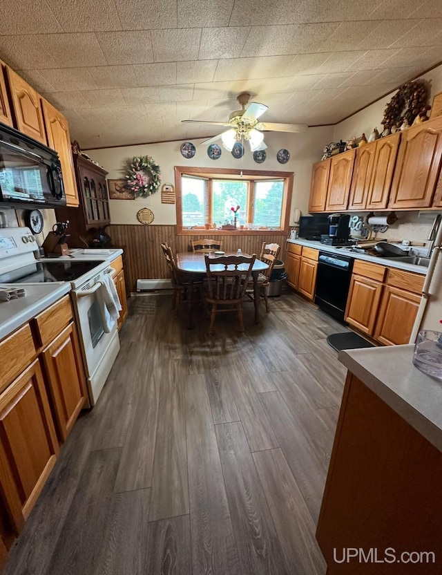 kitchen featuring wood walls, dark hardwood / wood-style flooring, ceiling fan, and black appliances