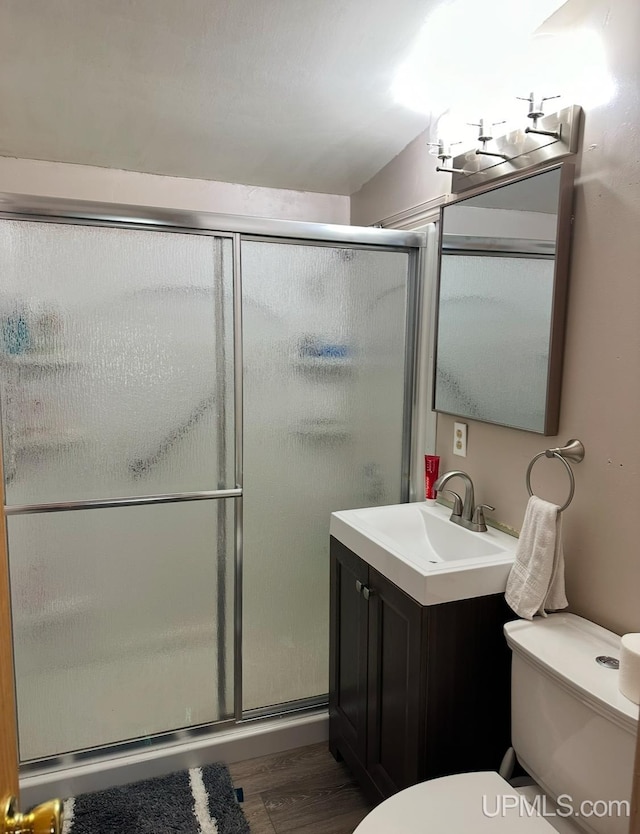 bathroom featuring hardwood / wood-style floors, vanity, toilet, and a shower with shower door