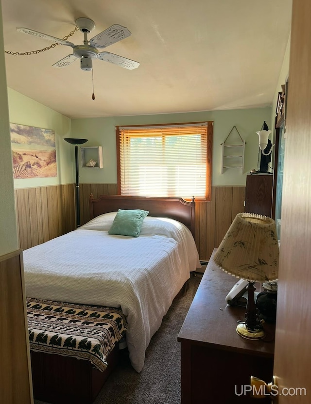 carpeted bedroom featuring ceiling fan and wooden walls