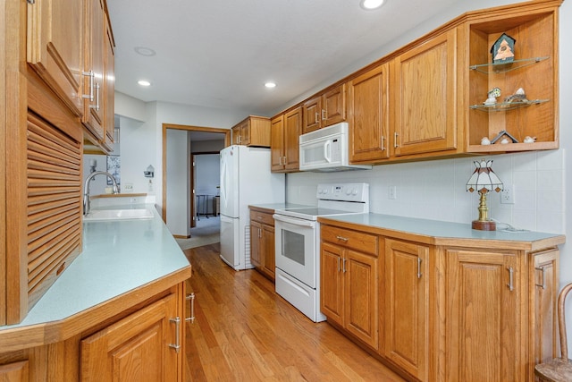 kitchen featuring decorative backsplash, white appliances, light hardwood / wood-style floors, and sink