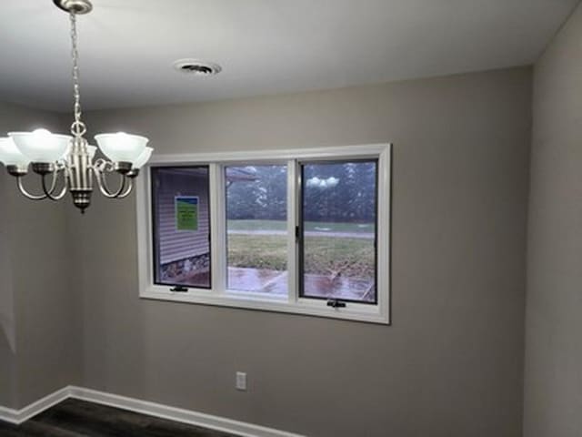 unfurnished room featuring dark hardwood / wood-style floors and a notable chandelier