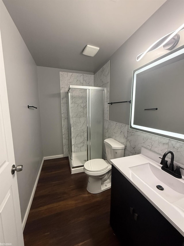 bathroom with a shower with door, vanity, wood-type flooring, and toilet