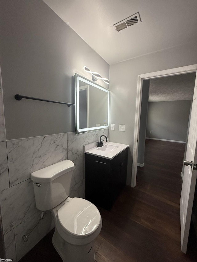 bathroom featuring hardwood / wood-style floors, vanity, tile walls, and toilet