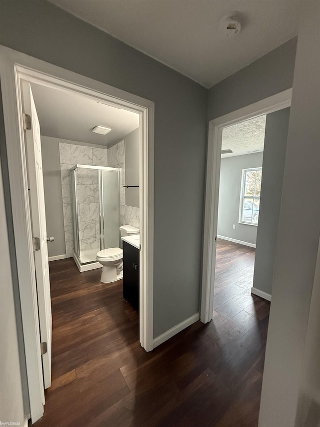 corridor with a textured ceiling and dark hardwood / wood-style floors