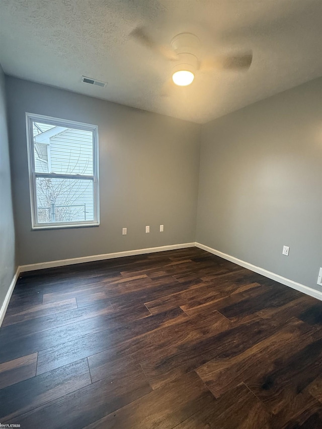 spare room featuring a textured ceiling and dark wood-type flooring