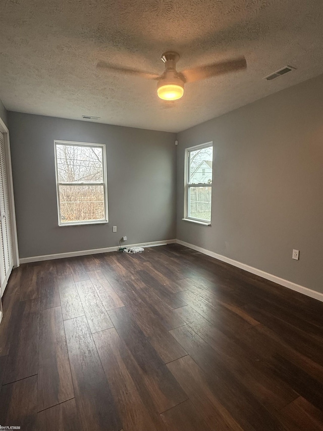 spare room featuring ceiling fan, a textured ceiling, and dark wood-type flooring