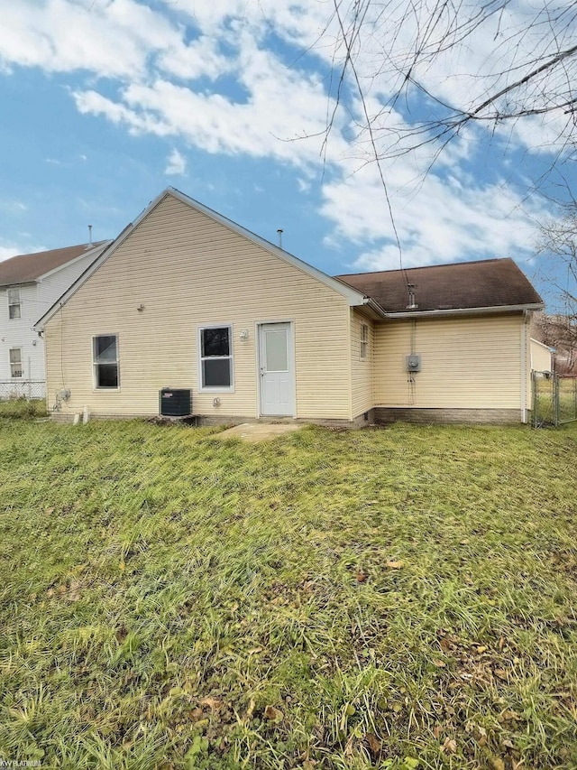 rear view of property featuring central AC unit and a lawn