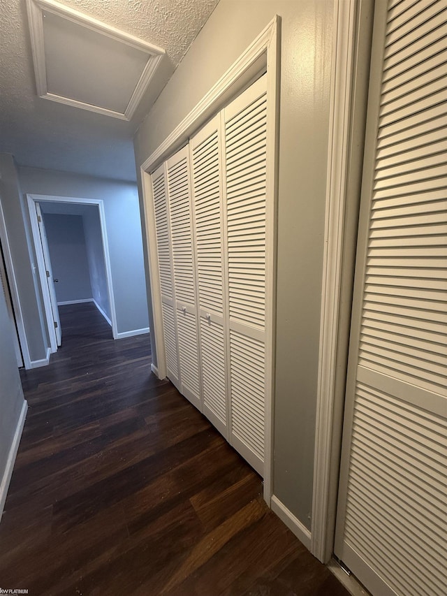 hall featuring a textured ceiling and dark hardwood / wood-style floors